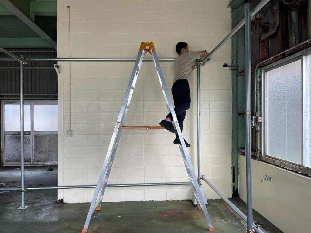 店主が工具を持って単管を組んでいる様子