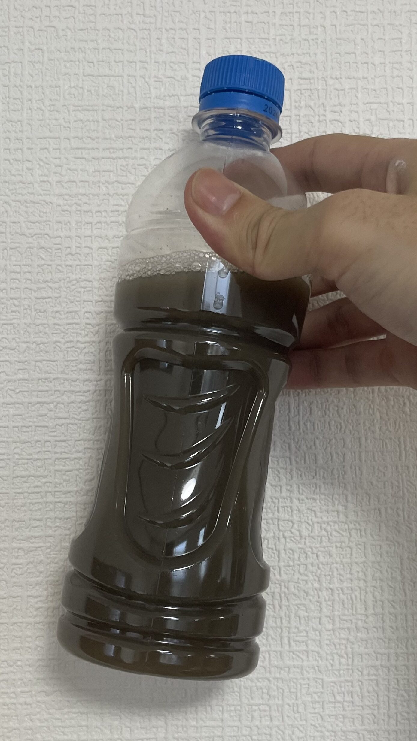 シートクリーニングで洗浄・すすぎで出た、焦茶色の水をペットボトルに採集してある写真