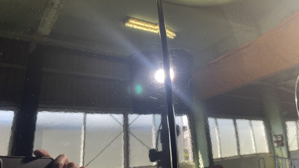 クリア塗装の曇りが取れているが、洗車傷が残っている黒い車の塗装面の写真
